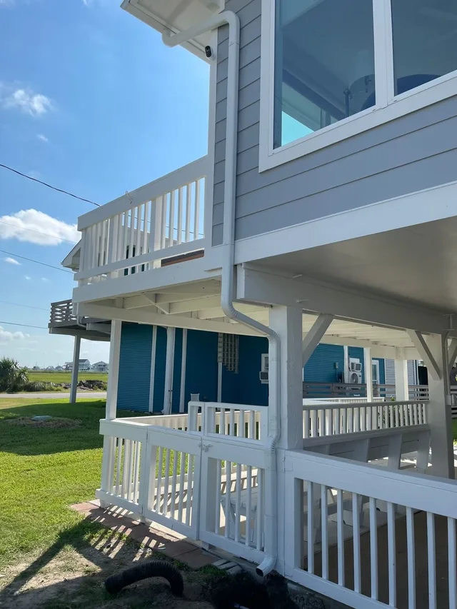 White downspout routing beside a raised coastal-style home